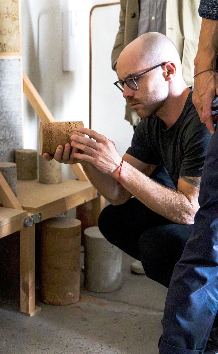 Portrait of Quentin Ferry examining a material sample in a workshop
