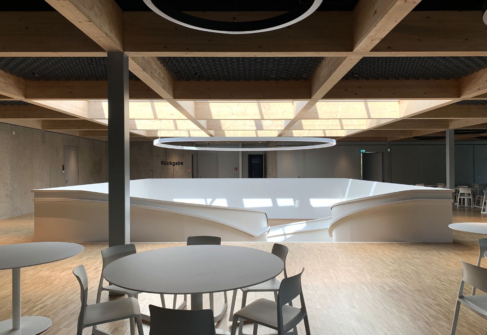 Mensa interior - sculptural white spiral staircase beneath an exposed timber ceiling